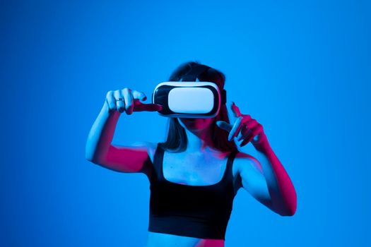 Brunette woman with VR headset touching something what she see in virtual world. Futuristic technology