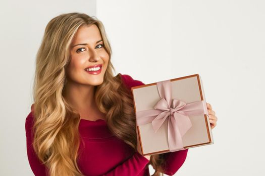 Happy woman holding a gift for birthday, anniversary, wedding, Valentines day or Christmas, luxury holiday present or beauty box subscription delivery concept