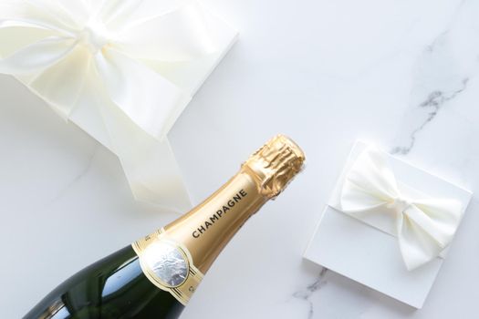 Wedding celebration, lifestyle and luxury present concept - A champagne bottle and a gift box on marble