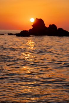 Beautiful view of orange sunset seascape with rocks in Italy. Tropical colourful sunrise landscape. Nature landscape. Tropical island coast
