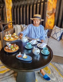 Asian women having a Luxury high tea with snacks and tea in a luxury hotel