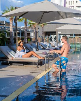 Rooftop swimming pool at a luxury hotel, luxury pool on a rooftop looking out over ocean. couple men and women on a rooftop swimming pool at a luxury hotel