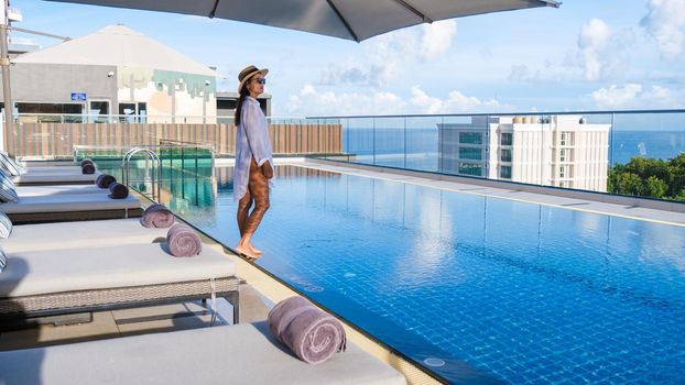 Asia women with a hat at a rooftop swimming pool at a luxury hotel,Rooftop swimming pool at a luxury hotel, luxury pool on a rooftop looking out over ocean