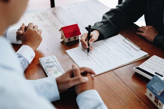 A couple is reading a home purchase contract before signing documents with a real estate agent.