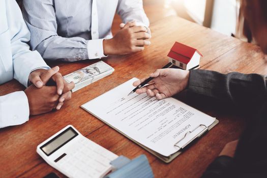 A couple is reading a home purchase contract before signing documents with a real estate agent.