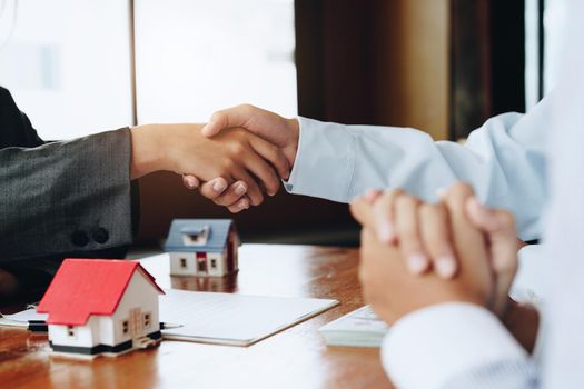 Real estate agents shake hands with customers after signing documents.