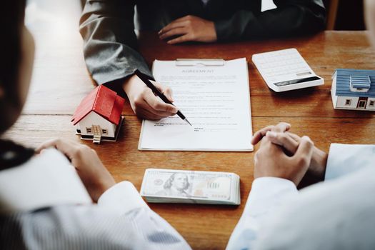 A couple is reading a home purchase contract before signing documents with a real estate agent.