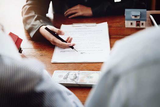 A couple is reading a home purchase contract before signing documents with a real estate agent.