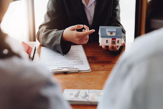 The real estate agent is showing the house model to the customer.