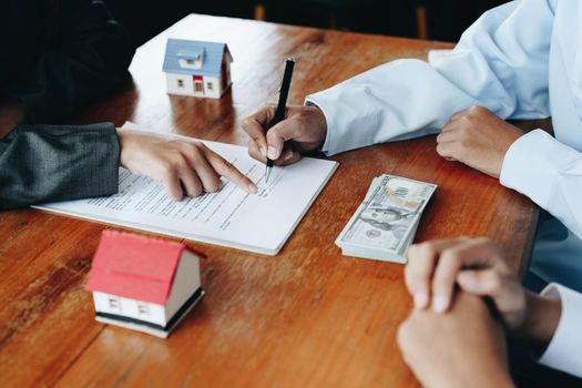 A couple is reading a home purchase contract before signing documents with a real estate agent.