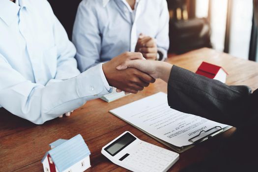 Real estate agents shake hands with customers after signing documents.