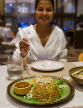 Fried rice mixed with yellow curry on a plate with hot chili sauce.