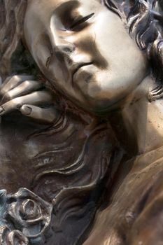Vintage sculpture of sad woman in grief. Virgin Mary bronze statue. Religion, faith, suffering, death concept.