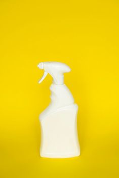 White detergent bottles or chemical cleaning supplies with a sprayer isolated on yellow background
