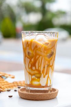 Iced caramel latte coffee in a tall glass with caramel syrup