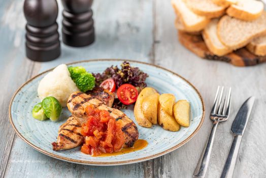 Grilled chicken breast in different variations with cherry tomatoes and different vegetables on wooden background