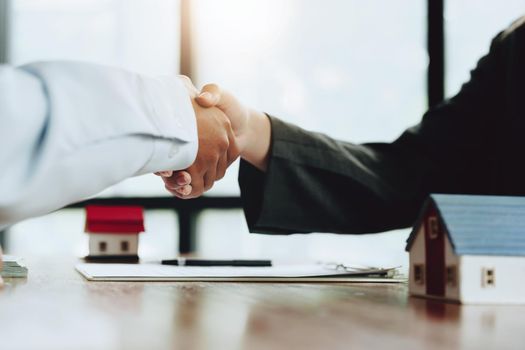 Real estate agents shake hands with customers after signing documents.