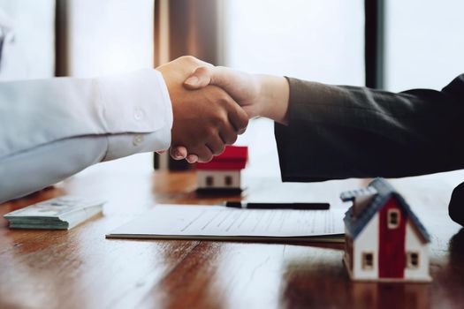 Real estate agents shake hands with customers after signing documents.