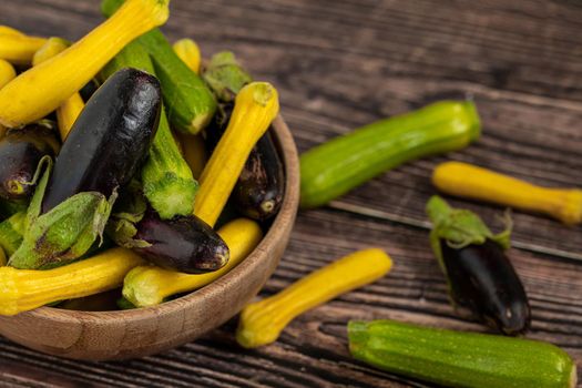 Baby Eggplant and zucchini in bamboo bowl on wooden table background