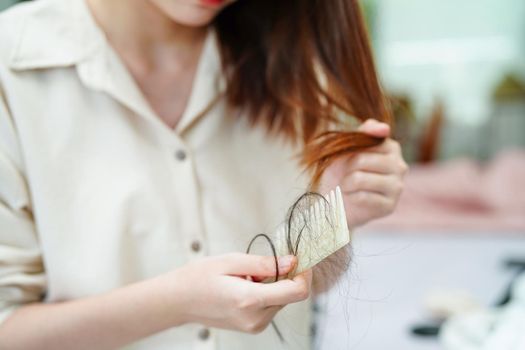 Asian woman have problem with long hair loss attach to comb brush.