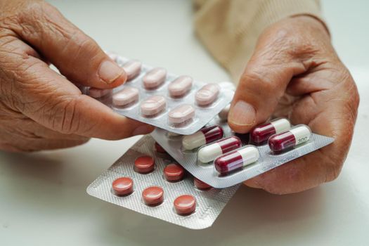 Asian elderly woman holding pill drug in hand, strong healthy medical concept.
