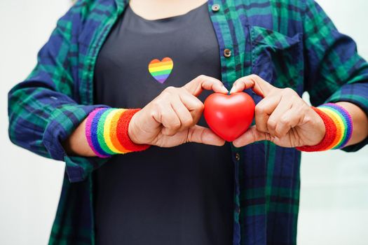 Asian woman holding red hert with rainbow flag, LGBT symbol rights and gender equality, LGBT Pride Month in June.