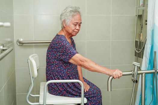Asian elderly old woman patient use toilet support rail in bathroom, handrail safety grab bar, security in nursing hospital.
