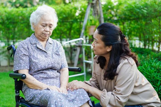 Caregiver help Asian elderly woman disability patient sitting on wheelchair in park, medical concept.