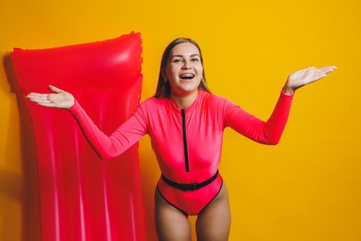 Young woman slim body pink one piece swimsuit on pink air mattress isolated on bright yellow color studio background summer hotel swimming pool sea vacation sun tanning concept. Place for text