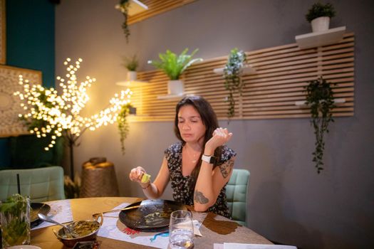 A hungry Hispanic girl is sitting in a restaurant and eating a delicious dinner alone.