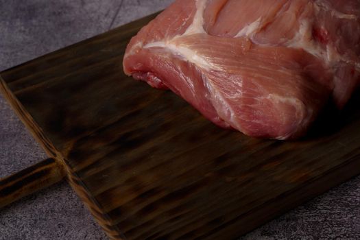 close-up of a piece of raw pork tenderloin on wooden board