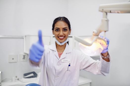 Here to help you maintain good oral health. Portrait of a young female dentist showing thumbs up in her office