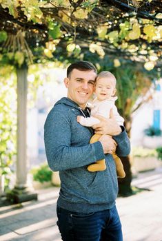 Smiling dad with a baby in his arms stands in the yard. High quality photo