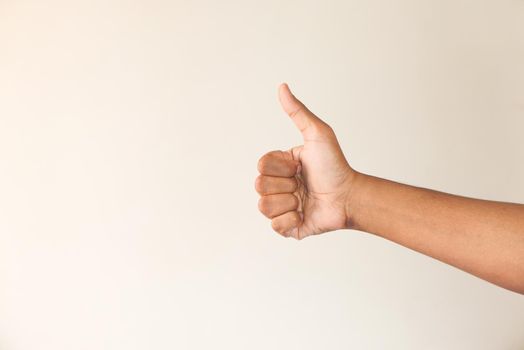 man's hand hand showing a thumb-up on white wall .