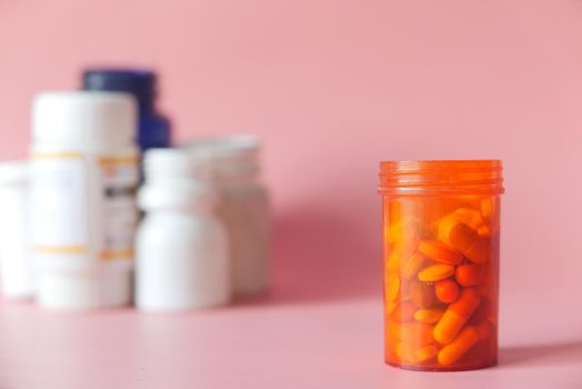 selective focus. close up of pills and capsule container on pink background .