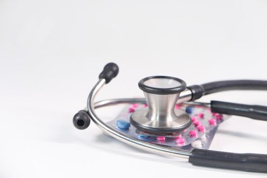 Close up of stethoscope and blister packs on white background .