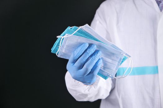 doctor hand in medical glove holding protective surgical face mask, close up .