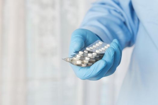 doctor hand in protective glass holding pill container.