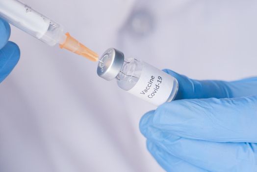 Doctor hands in medical gloves holds syringe and vaccine