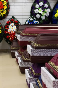 Interior of room with funeral accessories. Shop selling coffins, funeral wreaths and flowers.