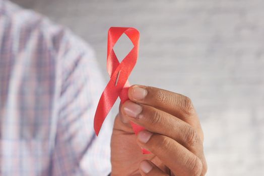 hand holding red HIV ribbon top down.