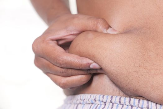 man's hand holding excessive belly fat, overweight concept.