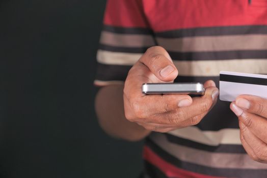 Man hand holding credit card and using smart phone shopping online .