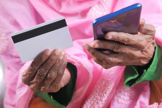 senior women hand holding credit card and using smart phone shopping online .