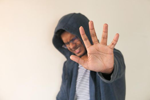 selective focus. young man show stop sigh against a wall