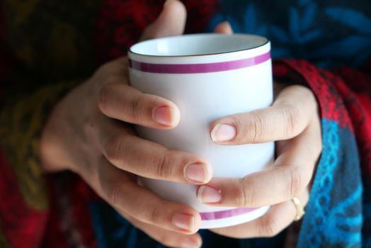 Close up of women's hand holding coffee mug .