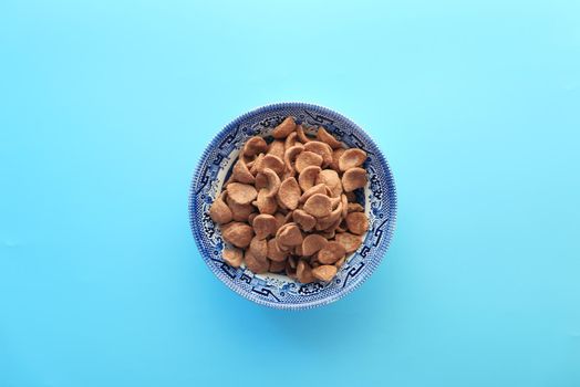 Top view of chocolate corn flakes in a bowl on blue .