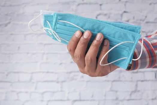 man hand holding surgical face mask, close up .