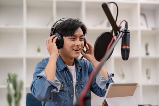 Asian male podcaster making audio podcast from her home studio.