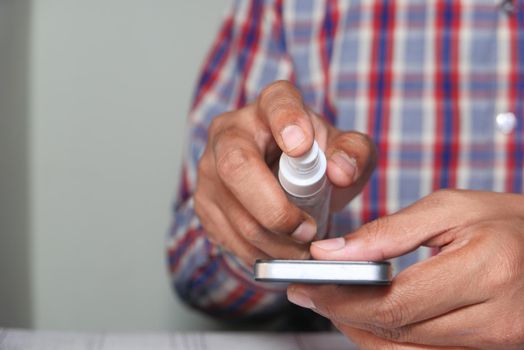 man hand disinfecting the smart phone screen with sanitize .